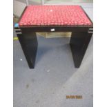 A contemporary black painted piano stool with fuschia pink upholstery