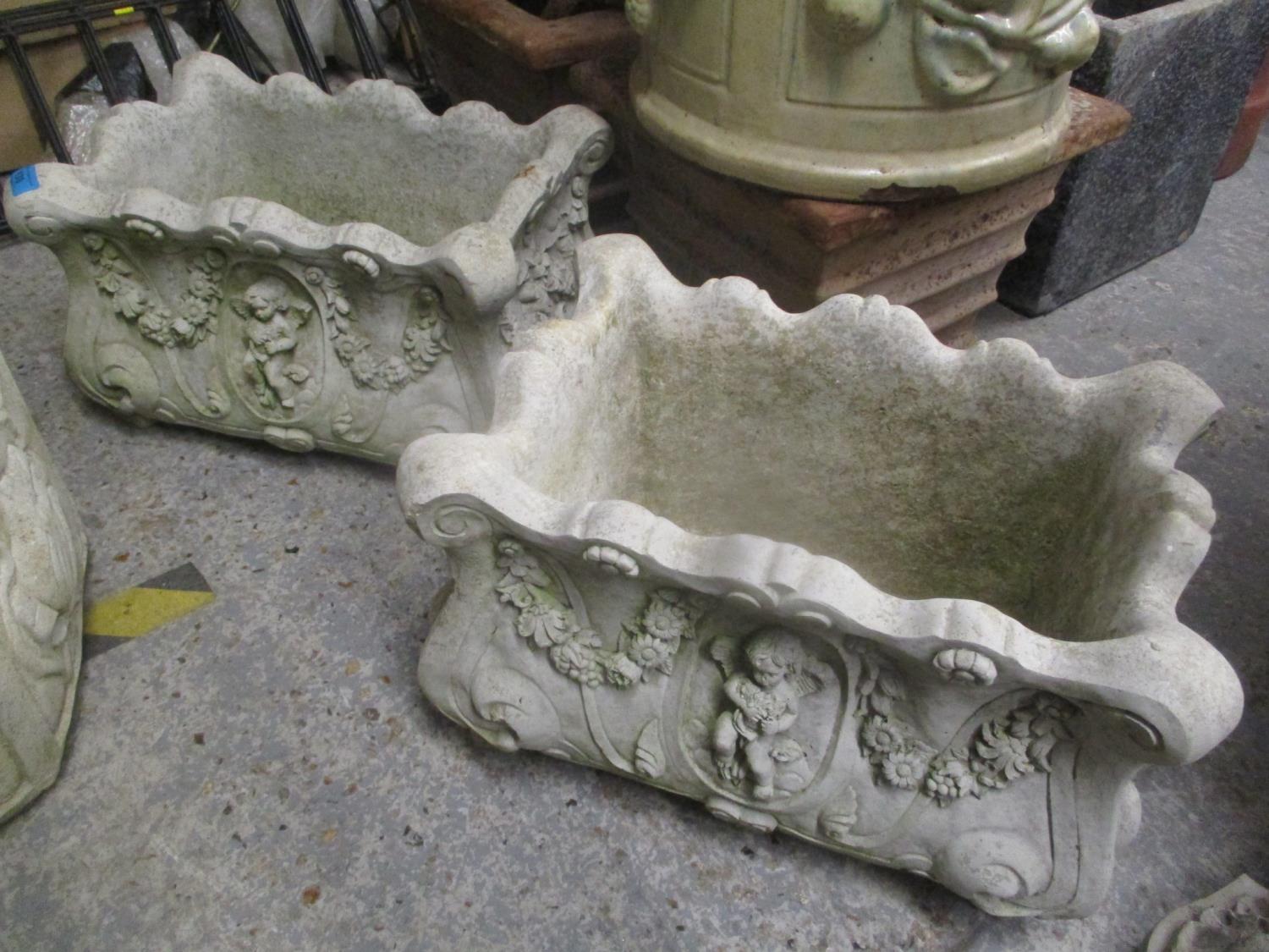 A pair of composition stone garden planters decorated with cherubs and floral swags 10" H x 16 1/