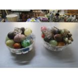 Two glass bowls containing a selection of stone and glass ornamental eggs and bunches of grapes