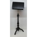 A Victorian ebonized music stand with an angle adjustable panel over a height adjustable brass