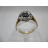 A gold and platinum coloured ring set with a central blue sapphire, set within a band of eight
