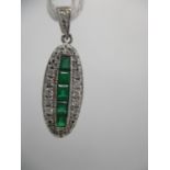 An 18ct white gold Art Deco style pendant set with a column of emeralds within a band of diamonds,