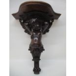 A late 19th century continental carved lime wood wall bracket with later additional top, over a