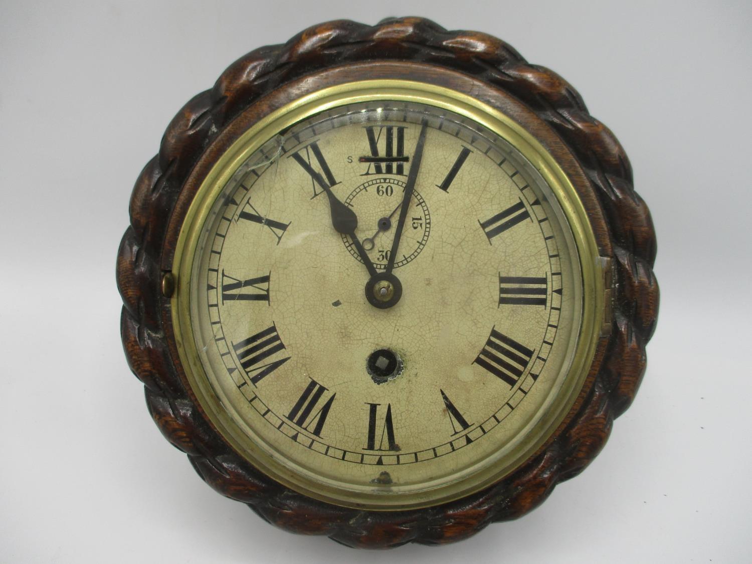 An early 20th century ships clock in an oak rope twist case, the dial having Roman numerals and a