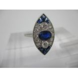 A platinum marquise shaped ring set with a central blue sapphire flanked by two larger diamonds