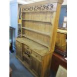 A pine dresser having a plate rack above three drawers, two cupboard doors and a poultry hatch, 80"h