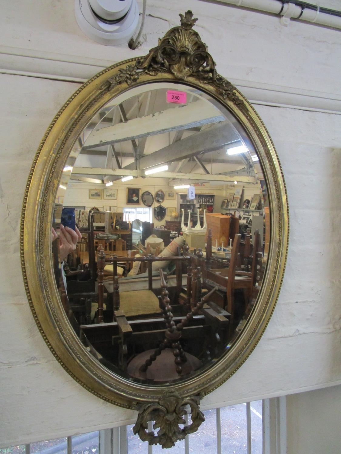 A late Victorian oval gilt framed wall mirror with scrolled leaf and styalized acanthus leaf