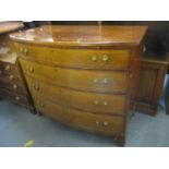 An early 19th century walnut bow fronted chest of four graduated drawers standing on bracket