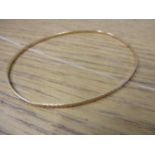 A gold coloured metal bangle stamped C18, 4.8g