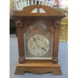 An early 20th century oak mantle clock having a silvered dial surrounded by gilt metal spandrels