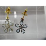 A pair of gold and silver daisy style earrings, each set with a central diamond surrounded by blue