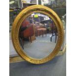 A contemporary oval gilt framed wall mirror with bevelled glass plate 28 1/2" x 24 1/2"