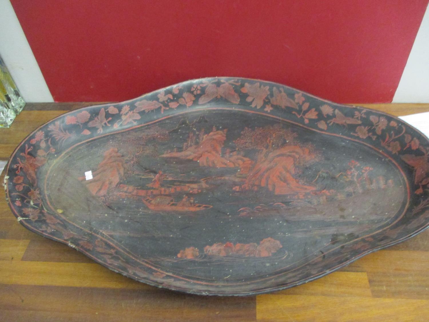 A large Oriental black papermache tray with red painted scenes