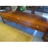 A retro teak coffee table having three double sided drawers above square legs