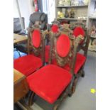 A set of six Victorian Gothic style carved oak dining chairs with bright red upholstered seats and