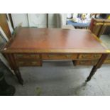 A late Victorian/Edwardian walnut desk, faded red leather inset scriber over five short drawers with