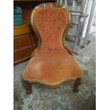 A Victorian walnut framed nursing chair, upholstered in a salmon pink colour, with carved crest rail