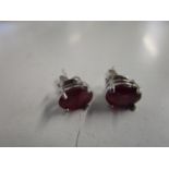 A pair of silver earrings, each set with a treated ruby