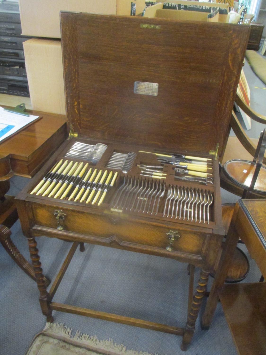 A 1920's oak Mappin & Webb cutlery table having a hinged top with drawer below containing fitted and