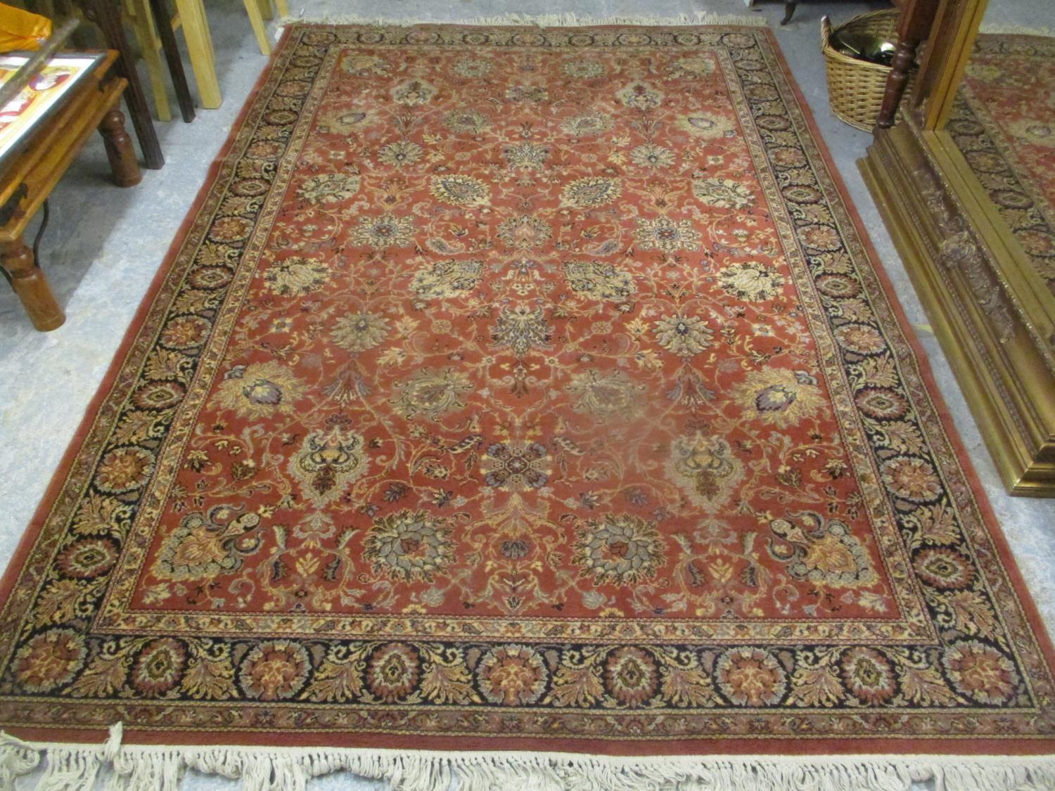 A machine woven red ground rug having a flora design and multiguard borders, 118" x 79"