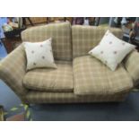 A modern two-seater sofa upholstered in a chequered pattern with loose cushions, on turned front