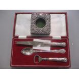 A Victorian silver fronted small photo-frame together with a cased cheese knife, pickle spoon and