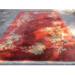 A Chinese red ground, machine woven rug having a floral design and tasselled ends, 140" x 97"