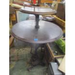 A modern two tier circular topped pub table on a wrought iron base, supported by two fish on