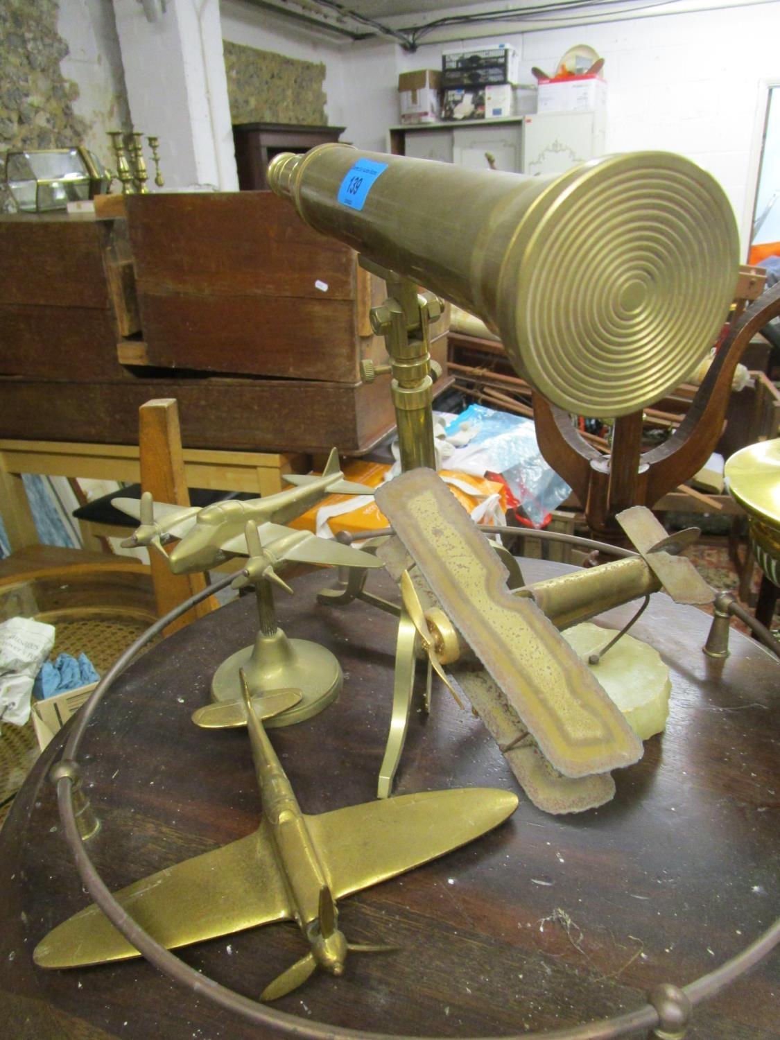 A reproduction brass telescope on tripod base, a metal model of a bi-plane mounted on an onyx