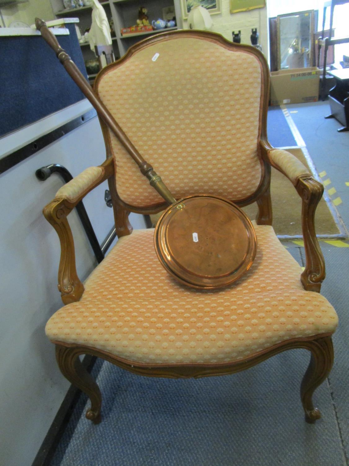 A salon armchair with peach coloured upholstery, together with a copper warming pan