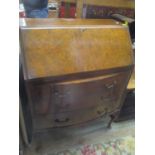 An early 20th century walnut bureau having a fall flap above three bow fronted drawers and on