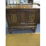 A 1930s/40s carved oak sideboard having two doors with carved coat of arms above two short drawers