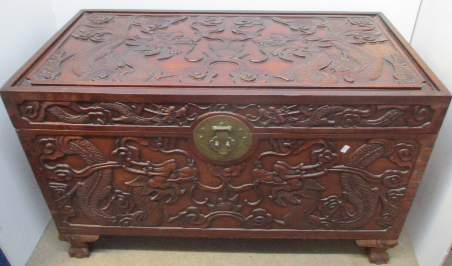 An early 20th century Chinese hardwood chest, the top, front and sides carved with dragons and