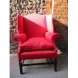 A George III wing back armchair upholstered in a red leaf patterned fabric, with a cushioned seat,