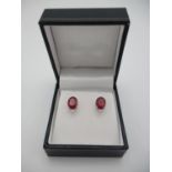 A pair of platinum stud earrings, each set with a treated ruby and a diamond below, rubies 4ct