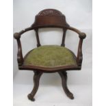 An early 20th century walnut desk chair with a fan carved crest, turned, curved arms, ball terminals
