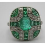 An Art Deco style platinum ring set with emeralds and diamonds in a cross style pattern