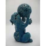 A 20th century Chinese blue glazed Foo dog on its haunches, holding up a ball, 9 1/2"h