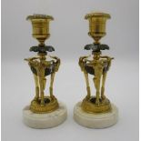 A pair of early 20th century French gilt metal candlesticks with rams head ornament and hoof feet on