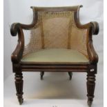 A Regency rosewood library chair with a scrolled crest and arms, caned back and sides, on turned,