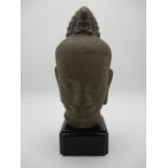 A 19th/20th century Indian/Pakistan carved stone head of a Buddha, with a figure to the tied up hair