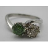 A platinum two stone diamond ring, the green diamond 0.69ct and a round cut diamond colour E-F,