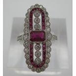 A platinum elongated ring set with a central ruby flanked by six diamonds within bands of diamonds
