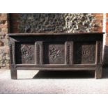 An 18th century oak chest with a hinged panelled top and carved, panelled front, on extended style