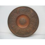 A late 19th century cast bronze and brass charger, the broad rim decorated with four heads,