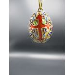 A yellow metal and enamel pendant in the form of an egg decorated with two crosses and scrolls 3/4"h