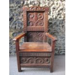 An 18th/19th century oak Wainscot chair with an arched carved crest, panelled back, level arms and