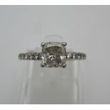 A platinum coloured diamond ring set with a single cushion diamond, measuring 5.7mm x 5.9mm,