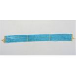 A multi strand turquoise bead choker with lined diamond separations and yellow metal hook, one of