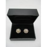 A pair of white and gold coloured metal earrings, each fashioned as a flower set with nineteen